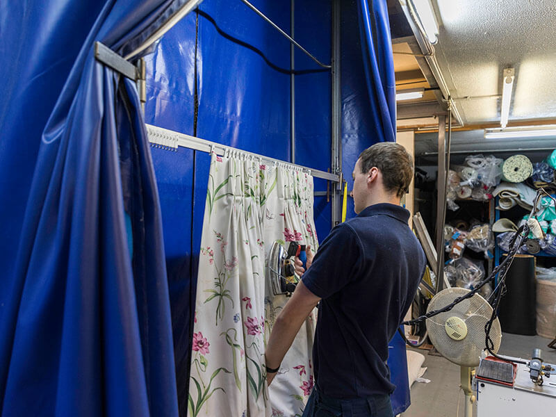 John Fredericks cleaning and ironing some curtains