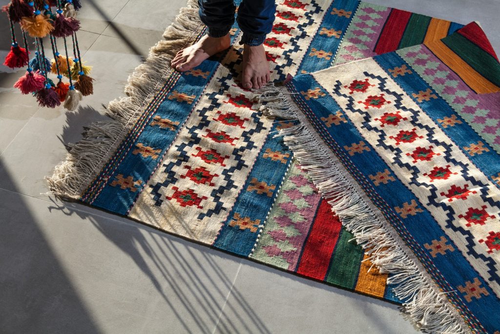 barefoot man standing on colourful rug